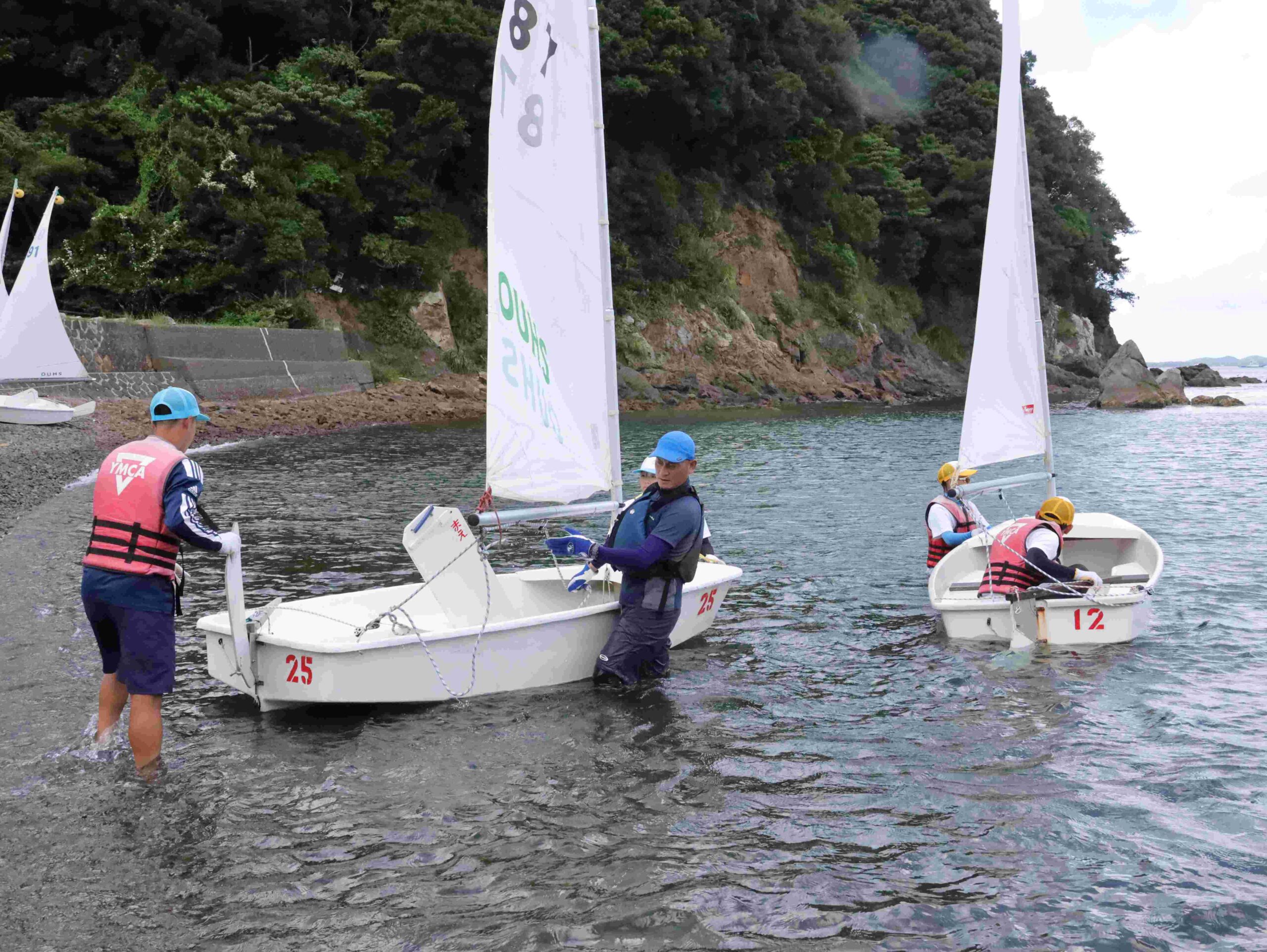 ＜ダックリン＝１人乗りヨット＞青帽は教員。中山健教授（スポーツ社会学）にサポートされてヨットに乗り込む